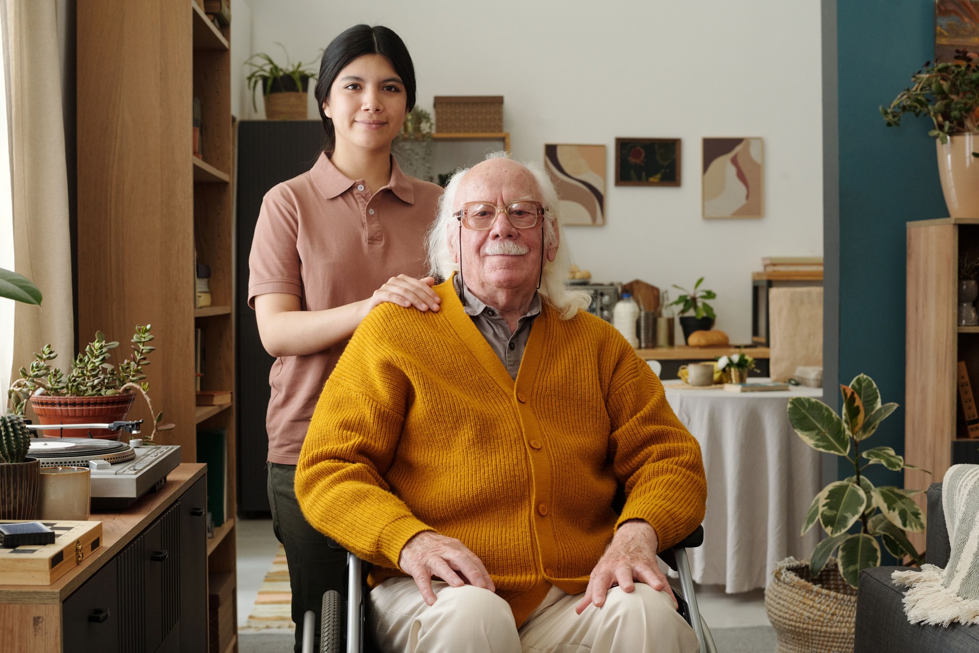 Portrait of Senior Man in Wheelchair Being Assisted by Young Adult Woman